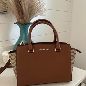This Cross body/ Hand bag from Michael Kors, And its brown.